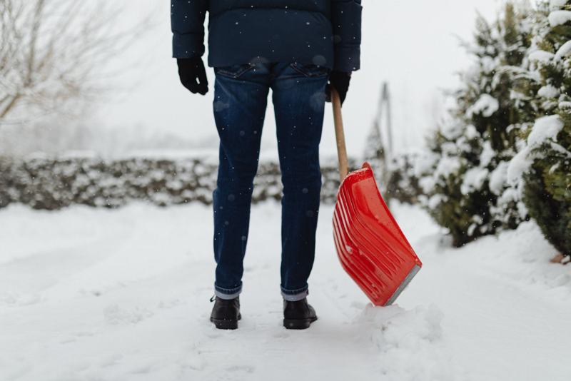 Person shoveling snow with a red shovel